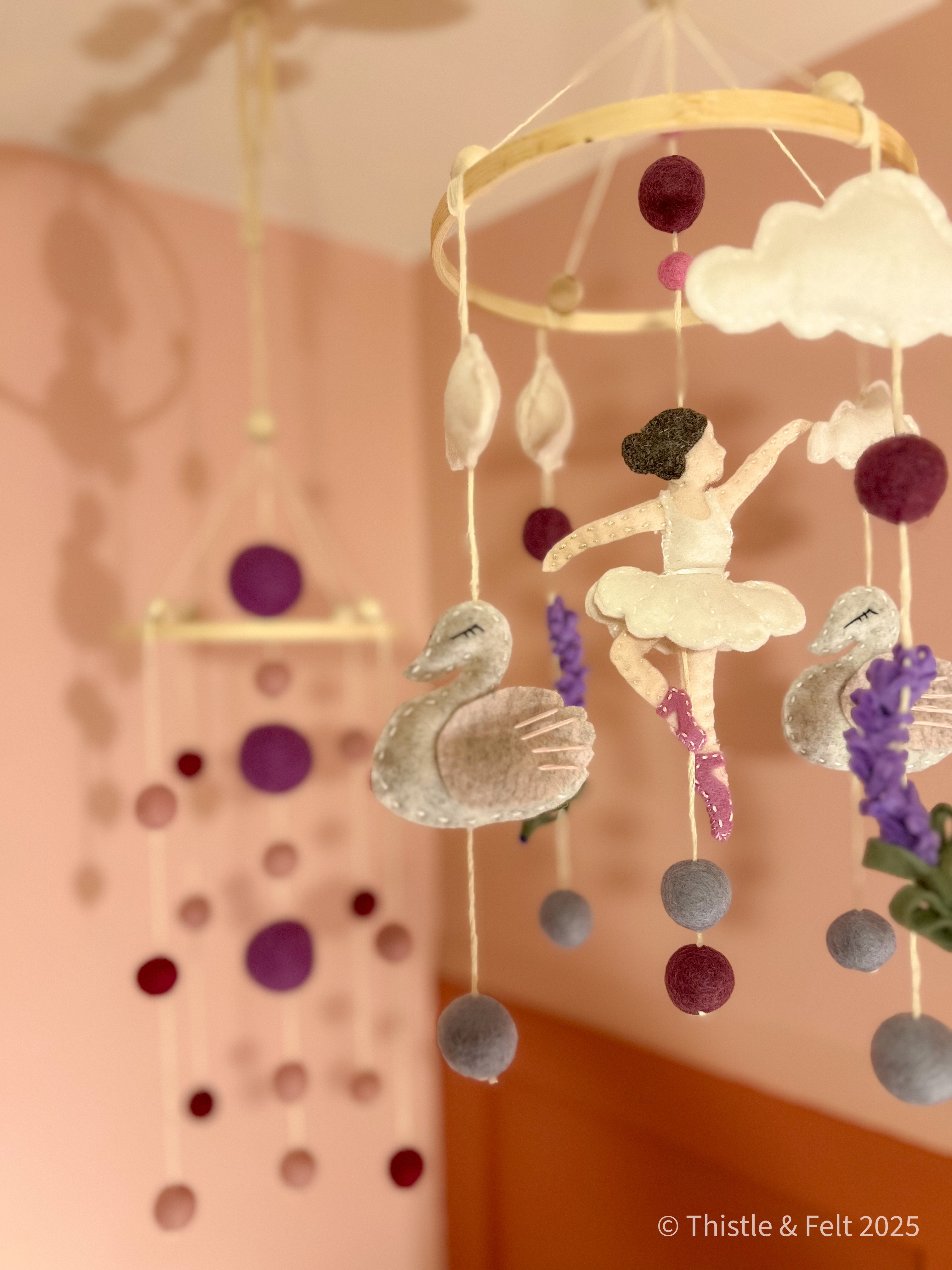 Handmade wool felt mobile featuring ballerina swans in soft pink and cream tones, inspired by classic fairytales.
