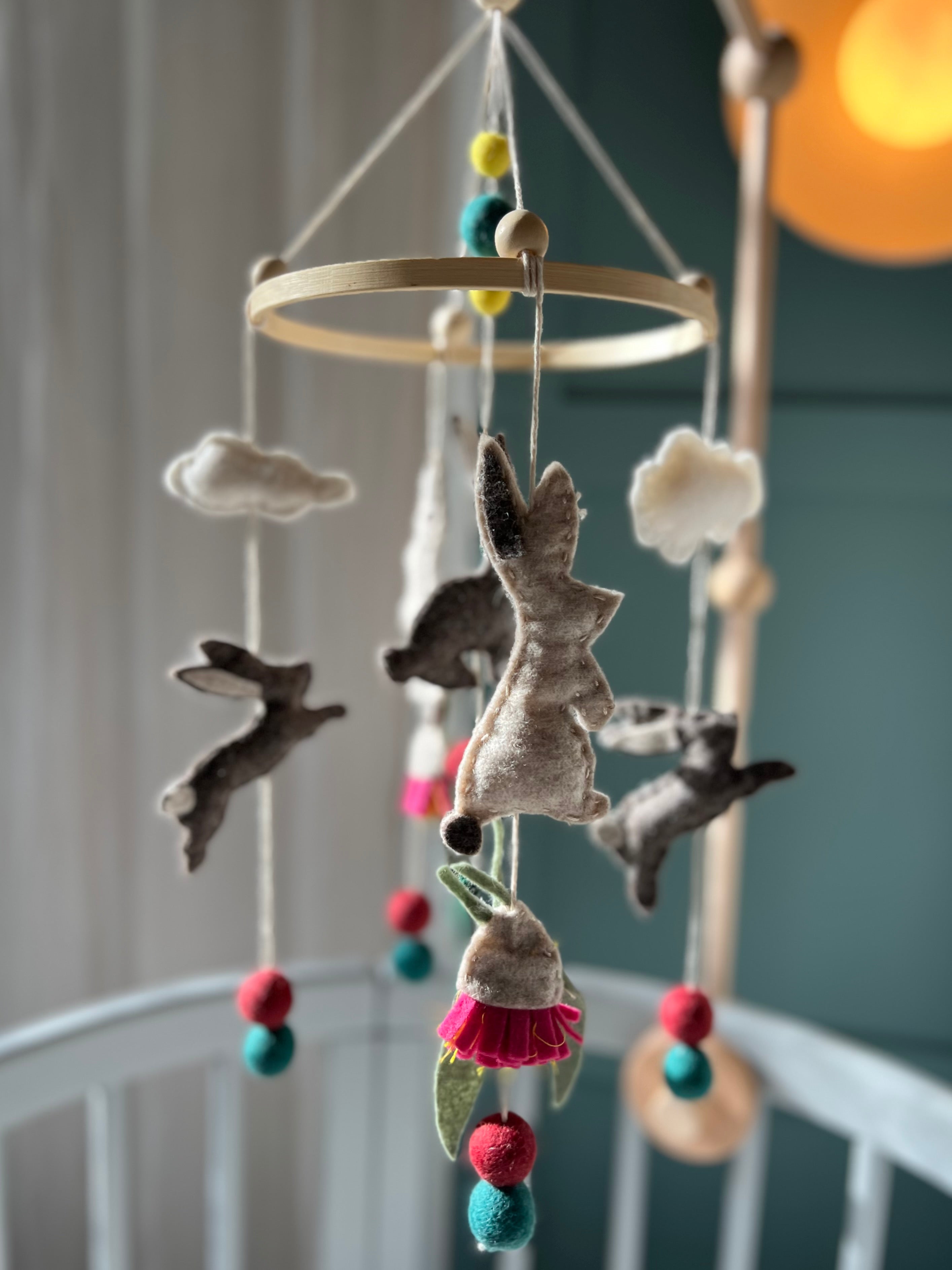 Pure wool felt nursery mobile with woodland bunnies and soft earthy colours, finished with a bamboo hoop by Thistle & Felt