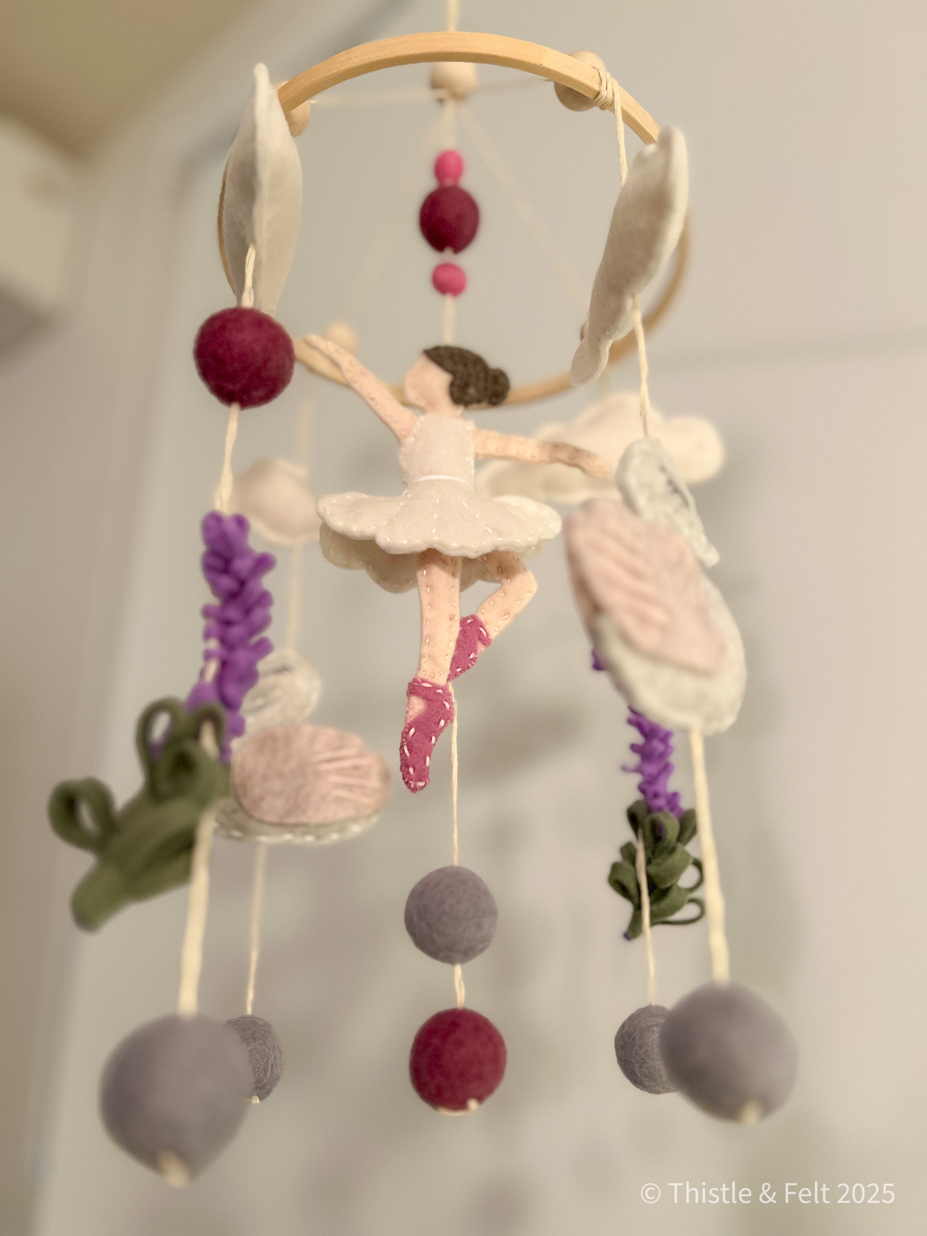 Handmade wool felt mobile featuring ballerina swans in soft pink and cream tones, inspired by classic fairytales.