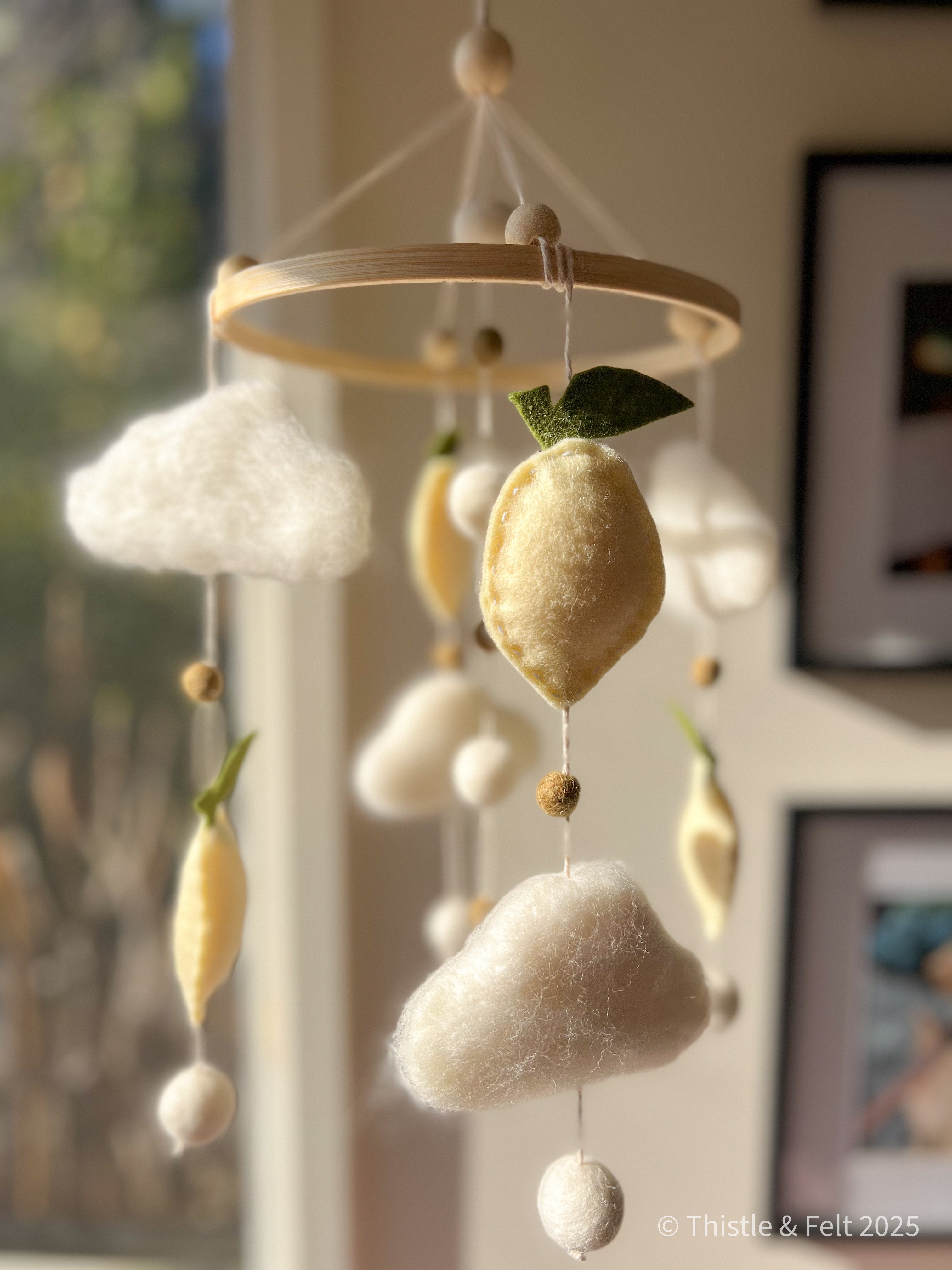 Handmade wool felt lemon nursery mobile with fluffy clouds by Thistle & Felt, perfect for natural nursery décor.