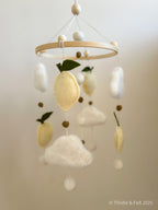 Handmade wool felt lemon nursery mobile with fluffy clouds by Thistle & Felt, perfect for natural nursery décor.