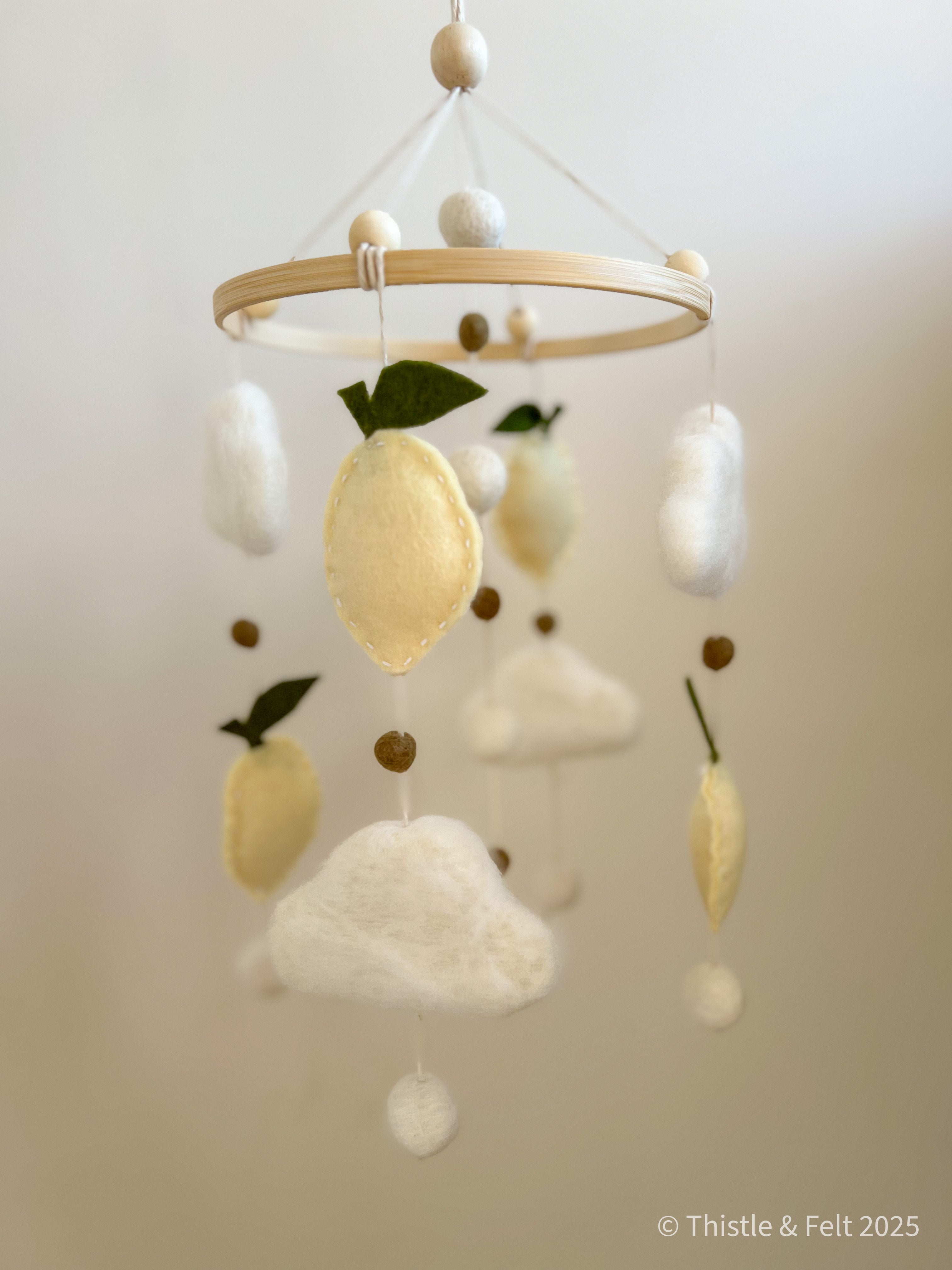 Handmade wool felt lemon nursery mobile with fluffy clouds by Thistle & Felt, perfect for natural nursery décor.