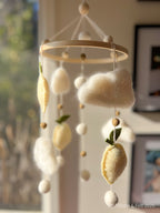 Handmade wool felt lemon nursery mobile with fluffy clouds by Thistle & Felt, perfect for natural nursery décor.