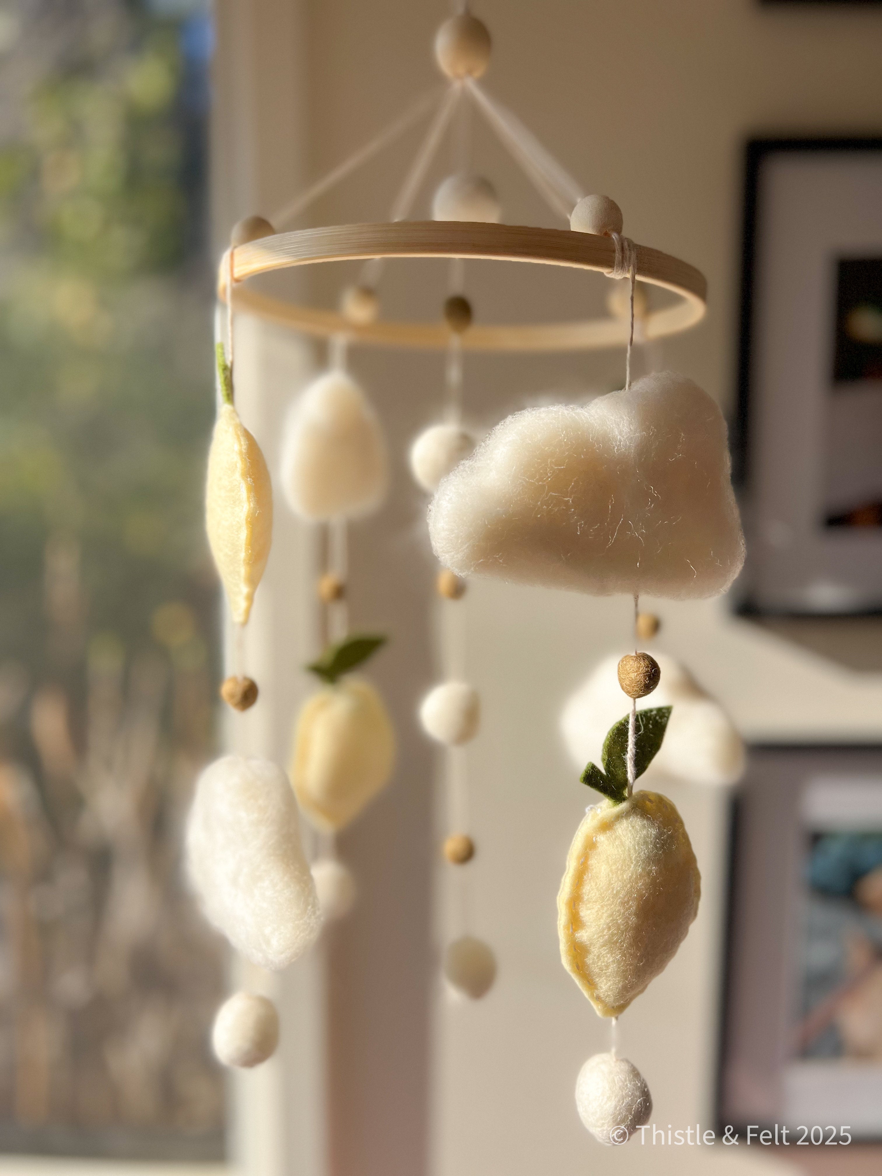 Handmade wool felt lemon nursery mobile with fluffy clouds by Thistle & Felt, perfect for natural nursery décor.