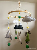 Handmade wool felt baby mobile featuring bunnies among mountain and pine details, with soft natural tone by Thistle & Felt