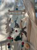 Pure wool felt nursery mobile with woodland bunnies and soft earthy colours, finished with a bamboo hoop by Thistle & Felt